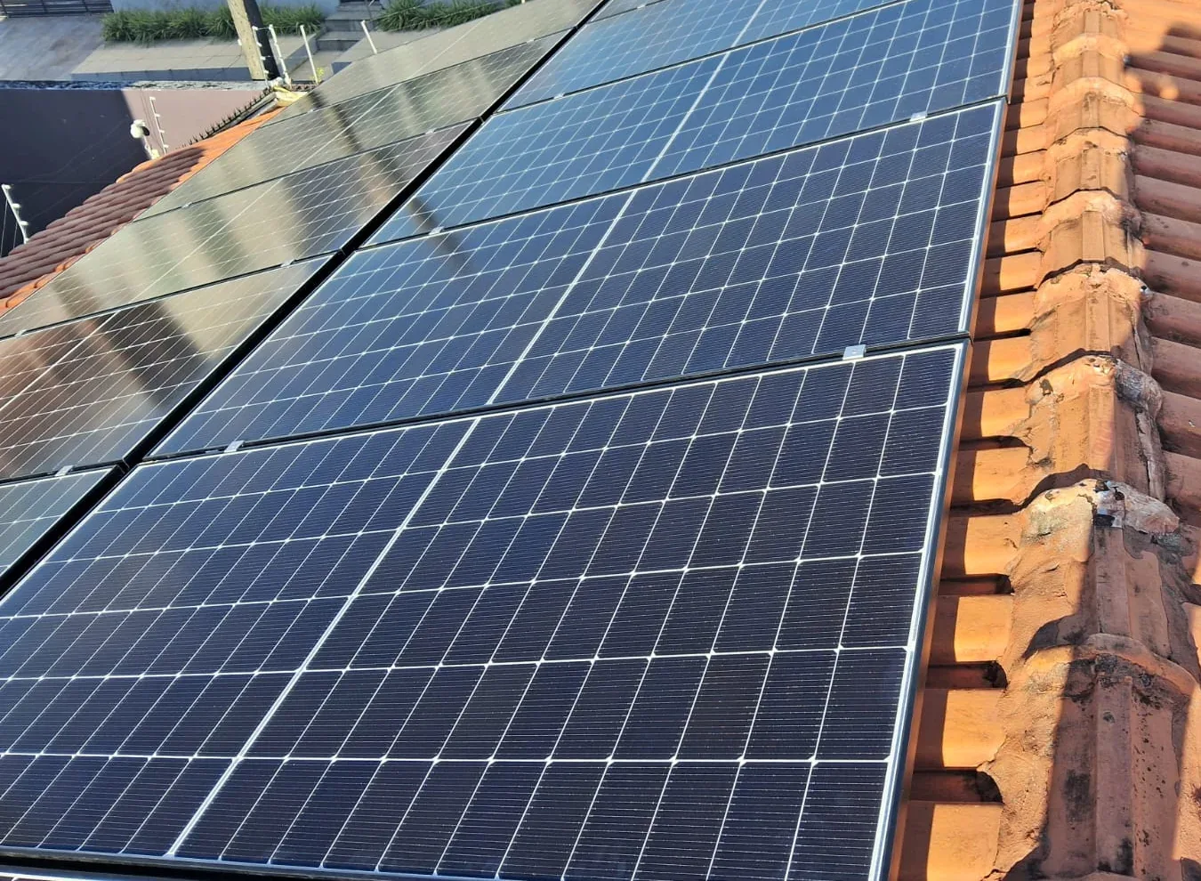 Módulos fotovoltaicos instalados sobre uma cobertura com telhas cerâmicas.