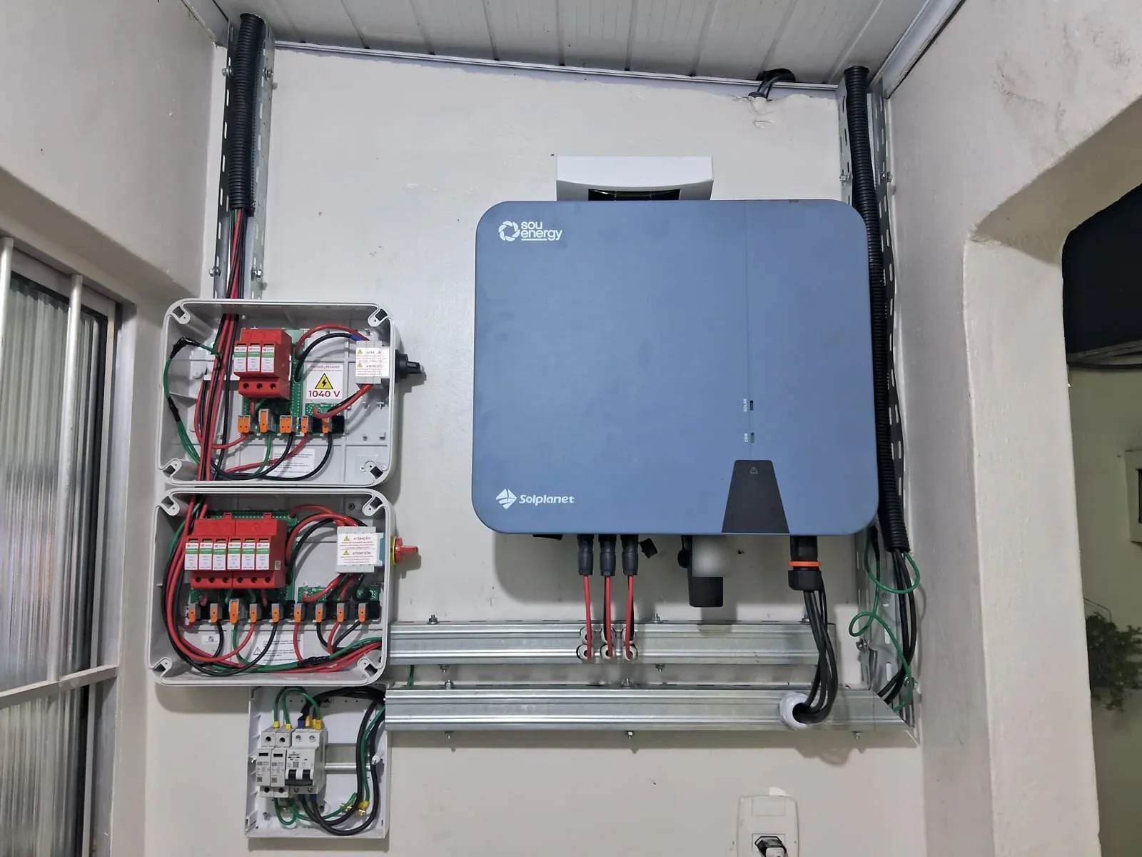 Inversor fotovoltaico instalado ao lado de componentes de proteção elétrica.